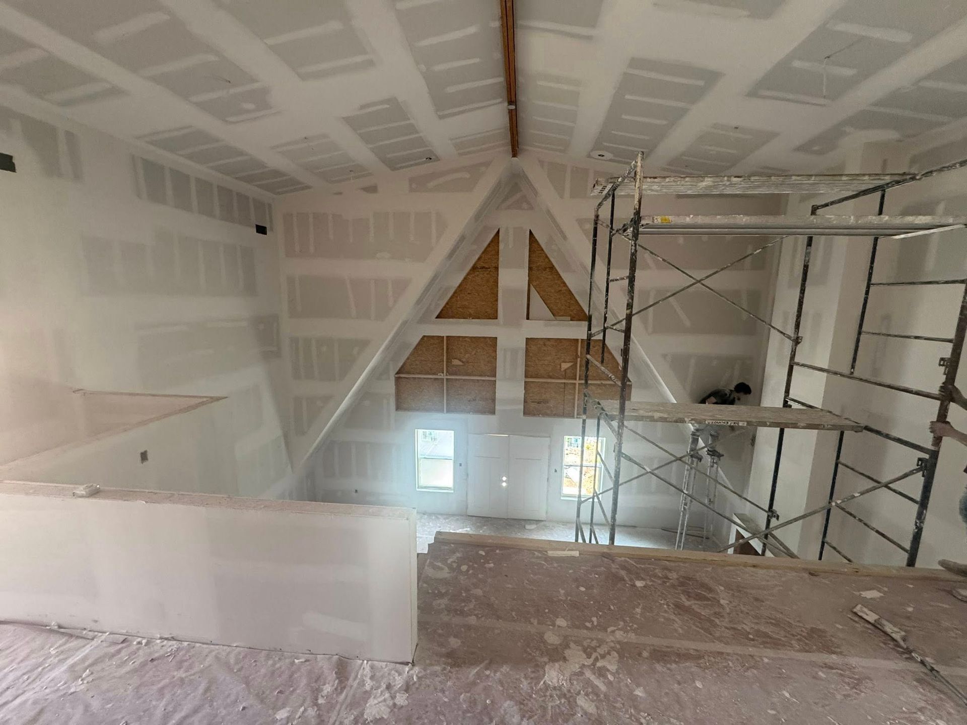 Interior of a house under construction. Drywall covers walls and ceiling, with a scaffolding visible.