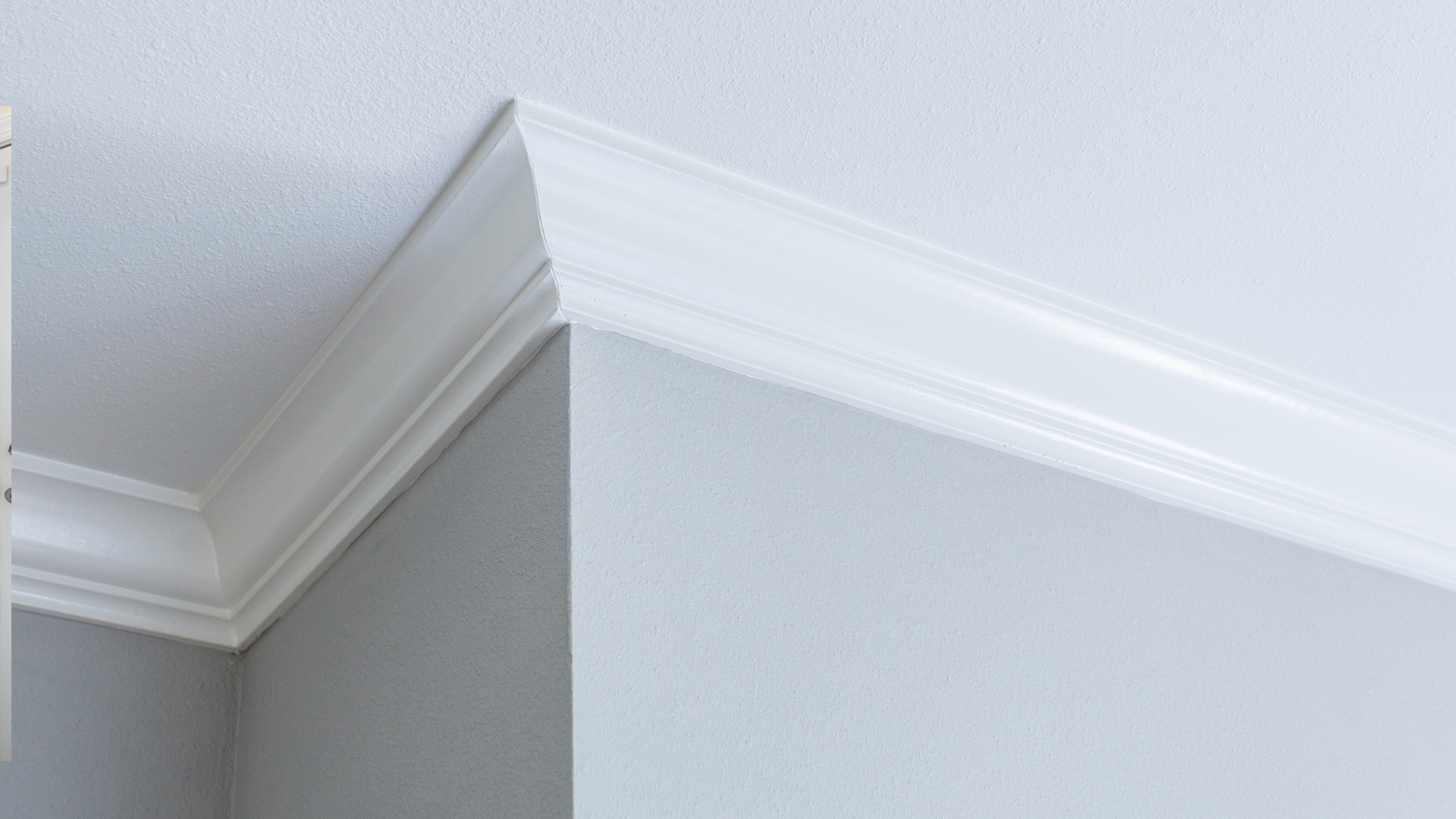 White crown molding at the juncture of a white ceiling and gray/white walls.