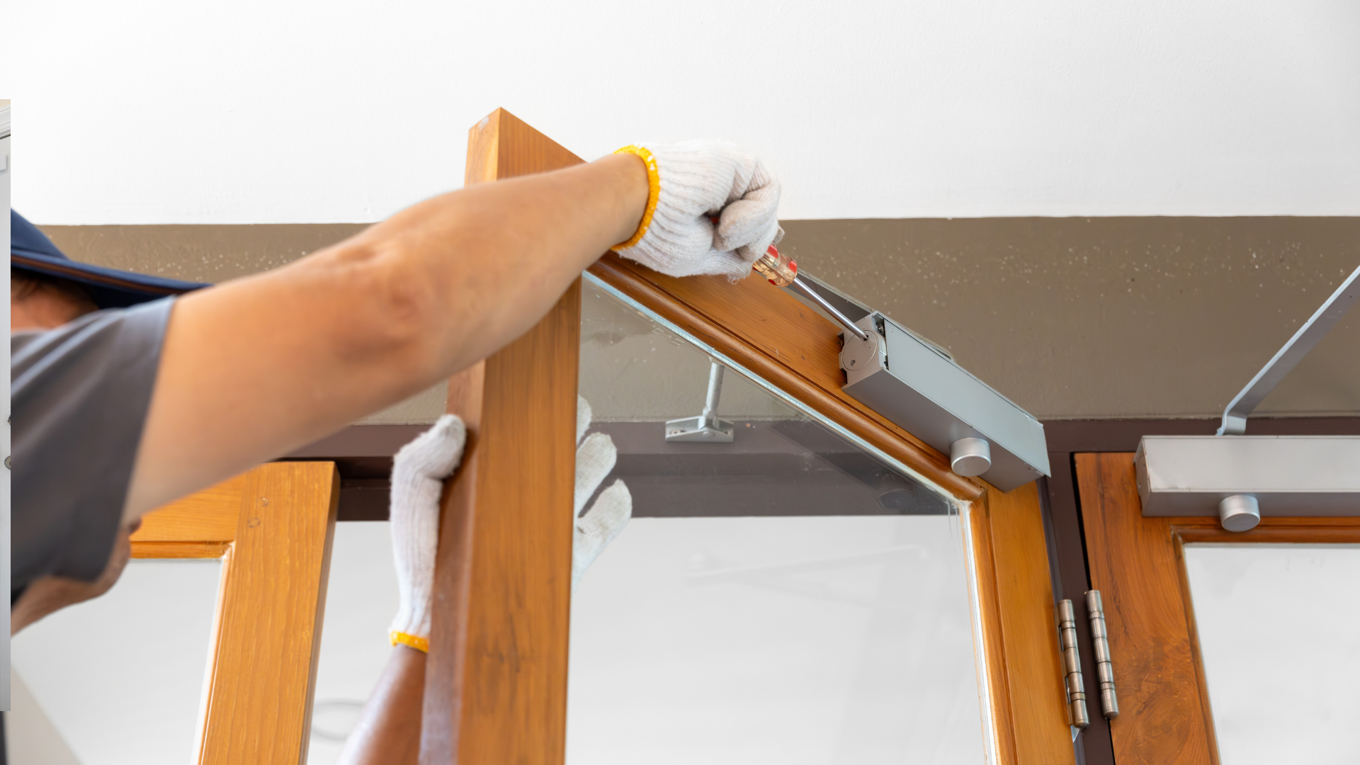Person installing a door closer on a wooden door frame.