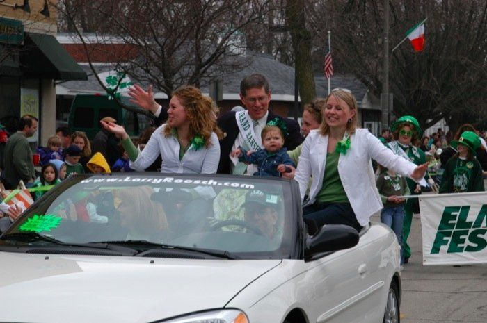 A group of people are riding in a car with a banner that says elm fest