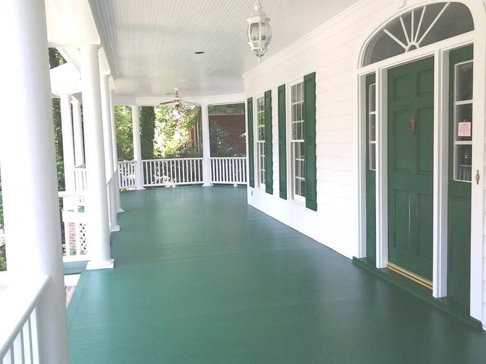 Green porch with white trim, columns, and a green door.