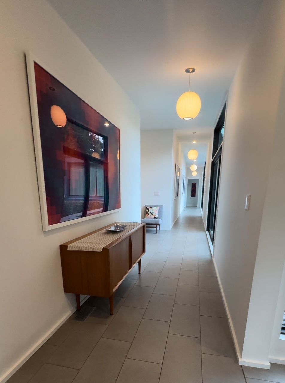 Long hallway with light fixtures, art, and a mid-century modern credenza.