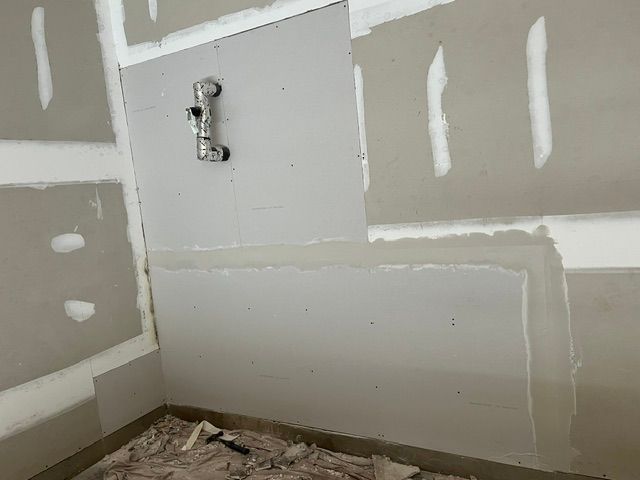 Interior view of a construction site with partially installed drywall, plumbing fixtures visible.