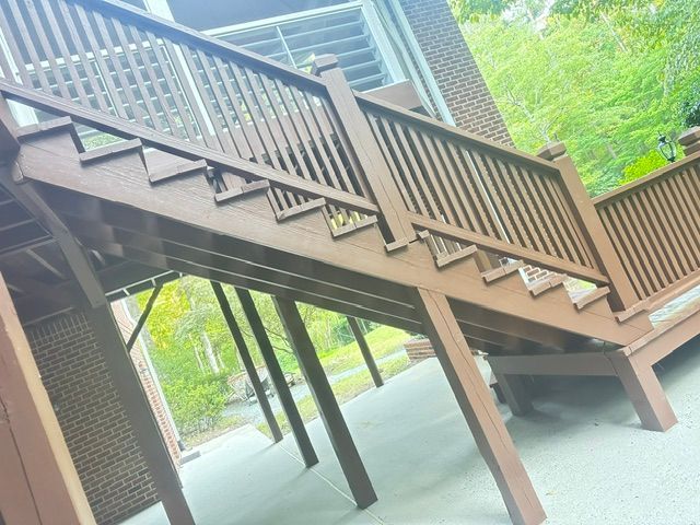 Brown wooden exterior staircase with railings, supported by angled posts, leading to an elevated deck.