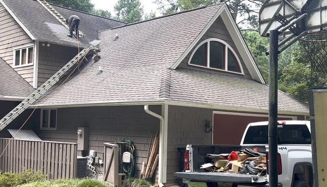 Empty living room with dark gray walls, hardwood floors, fireplace, built-in shelves, and double doors.