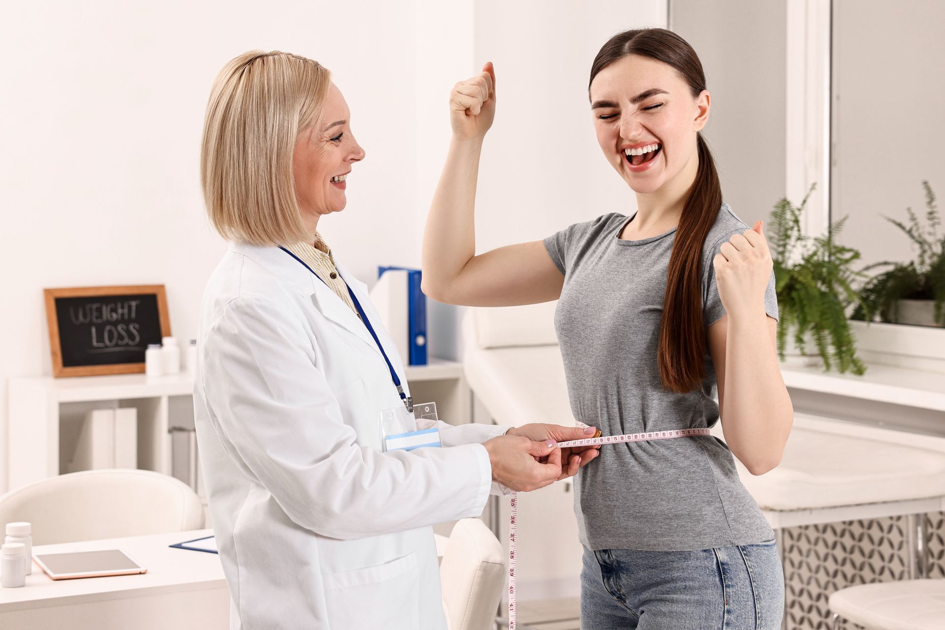A nutritionist is measuring a happy woman patient's waist in a clinic. A nutritionist is measuring a happy woman patient's waist in a clinic.