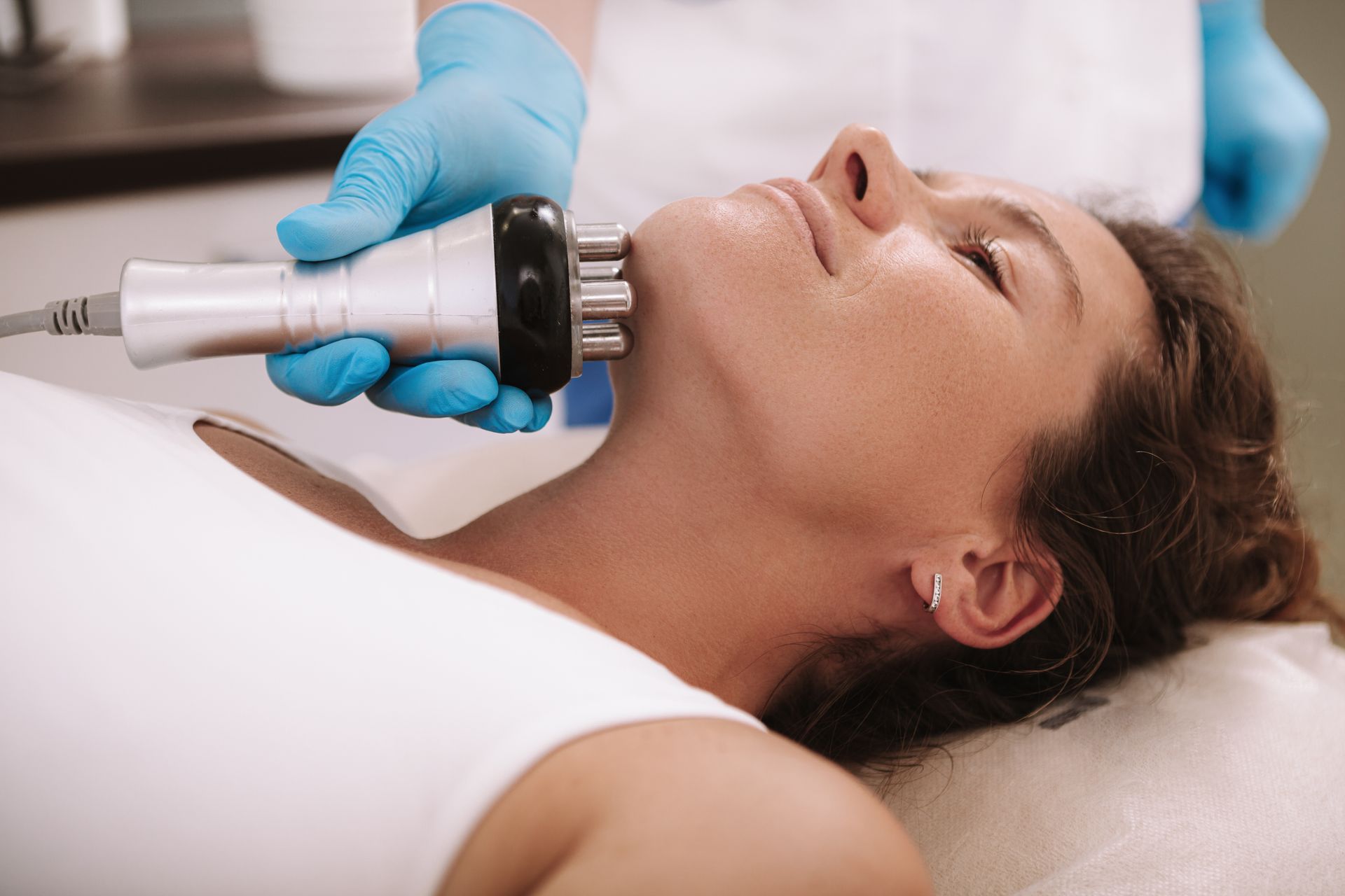A woman is getting skin-tightening treatment on her neck and chin A woman is getting skin-tightening treatment on her neck and chin