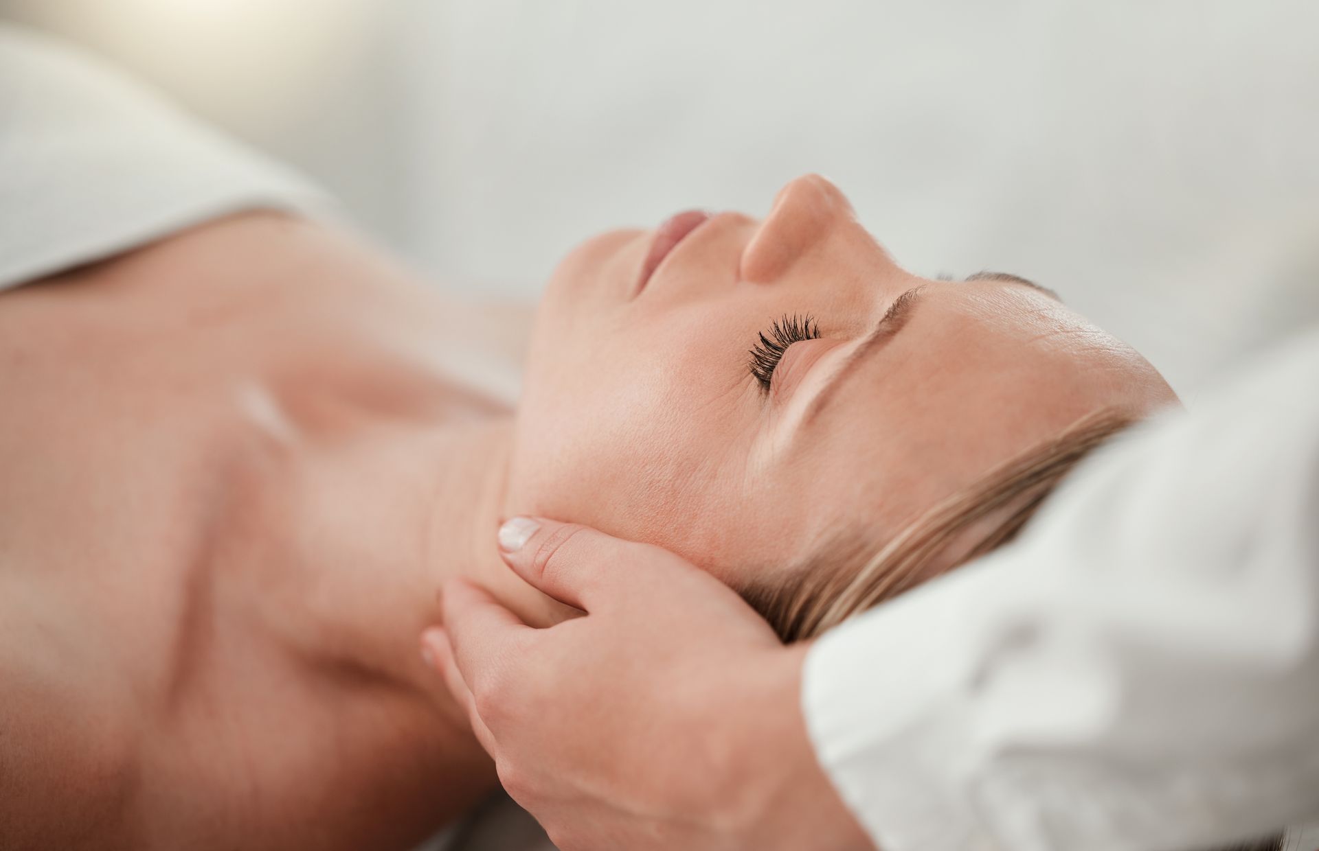 Person receiving a neck massage from a practitioner in a calming setting.
