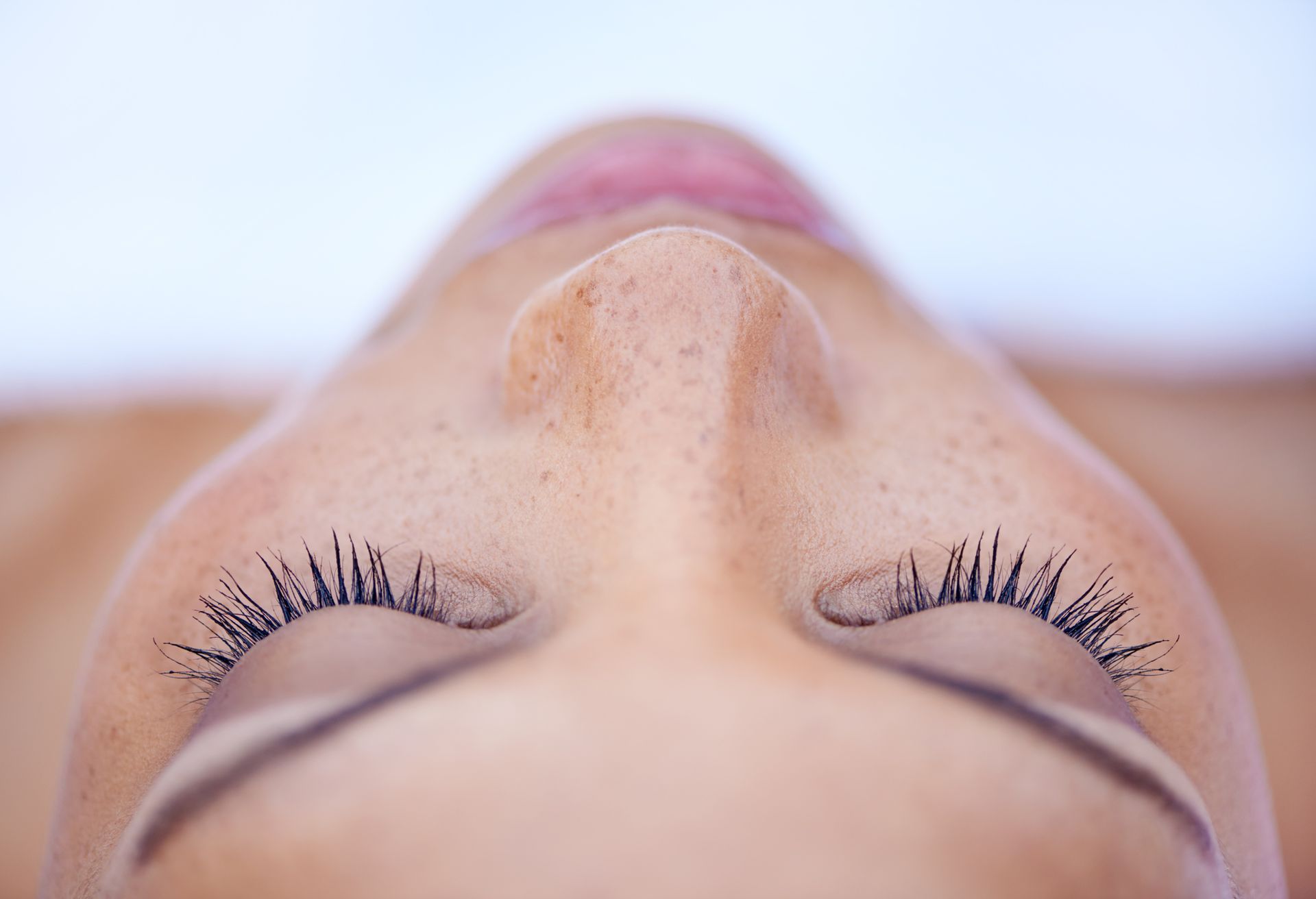 Close-up of person's face with closed eyes, viewed from nose upward.