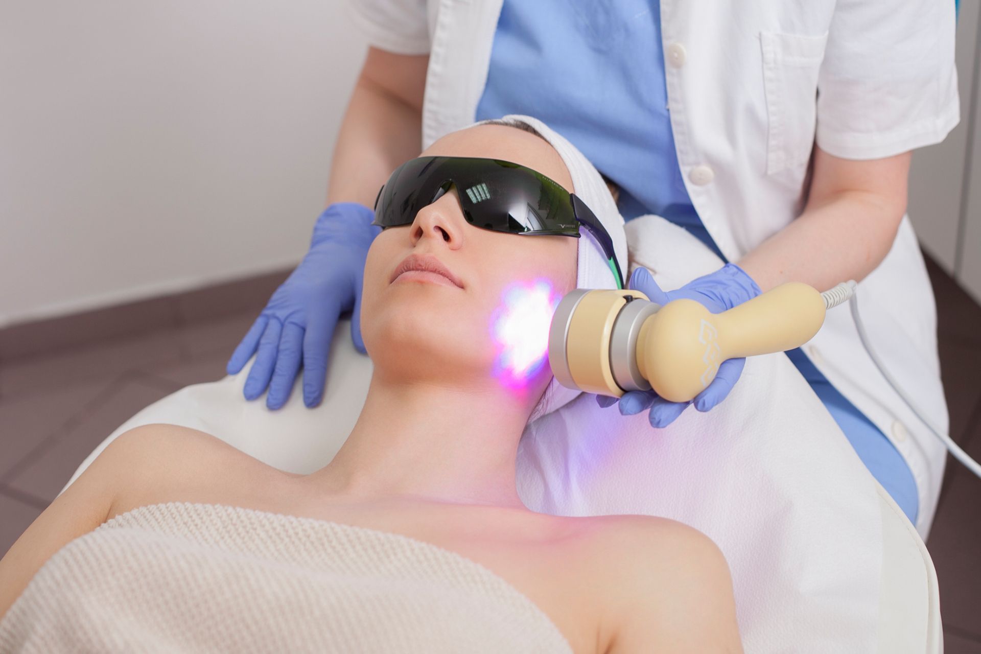 A woman is getting a laser treatment on her face. A woman is getting a laser treatment on her face.