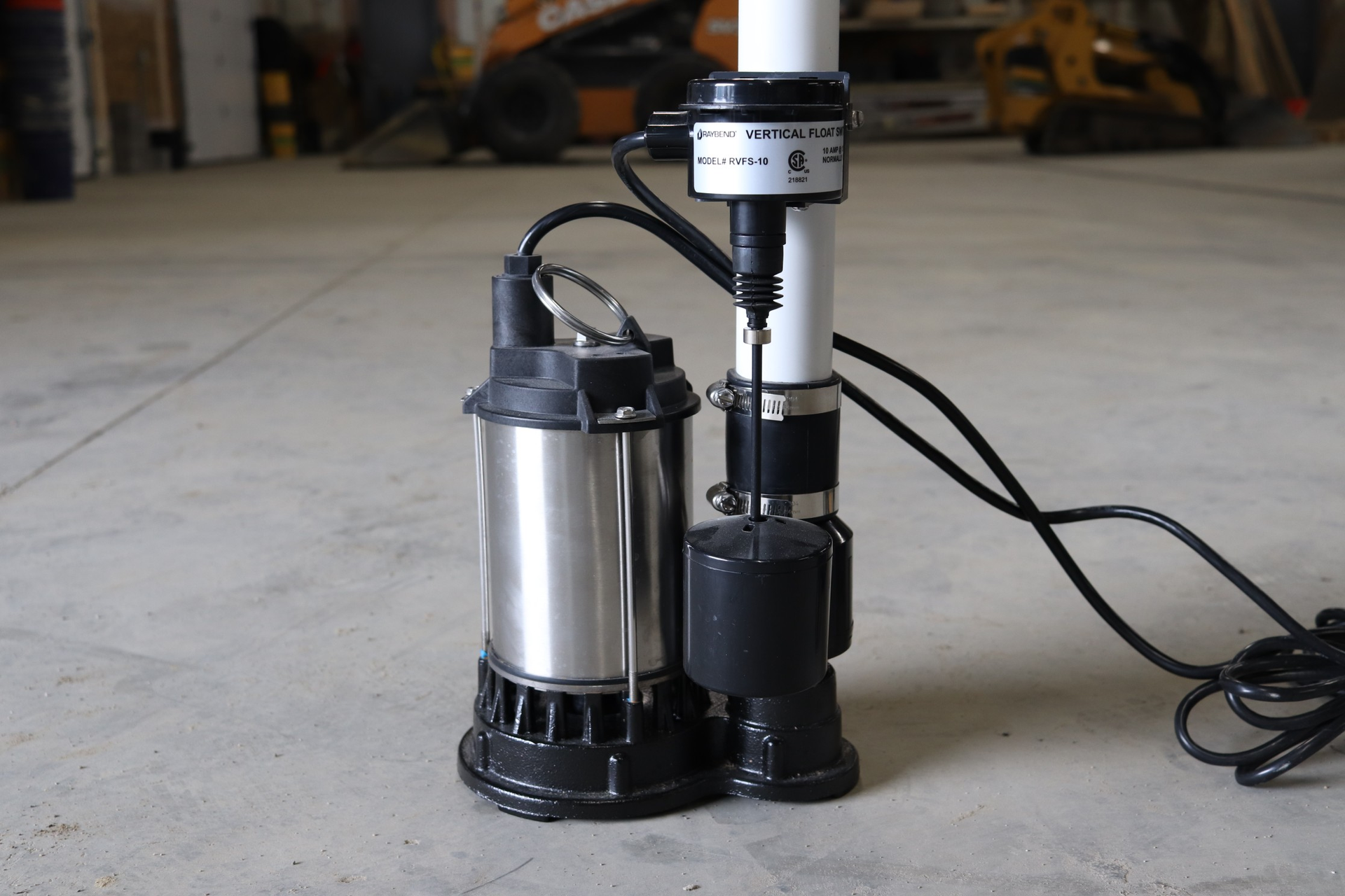 Sump pump with float switch, electrical cord, mounted on concrete floor, interior.