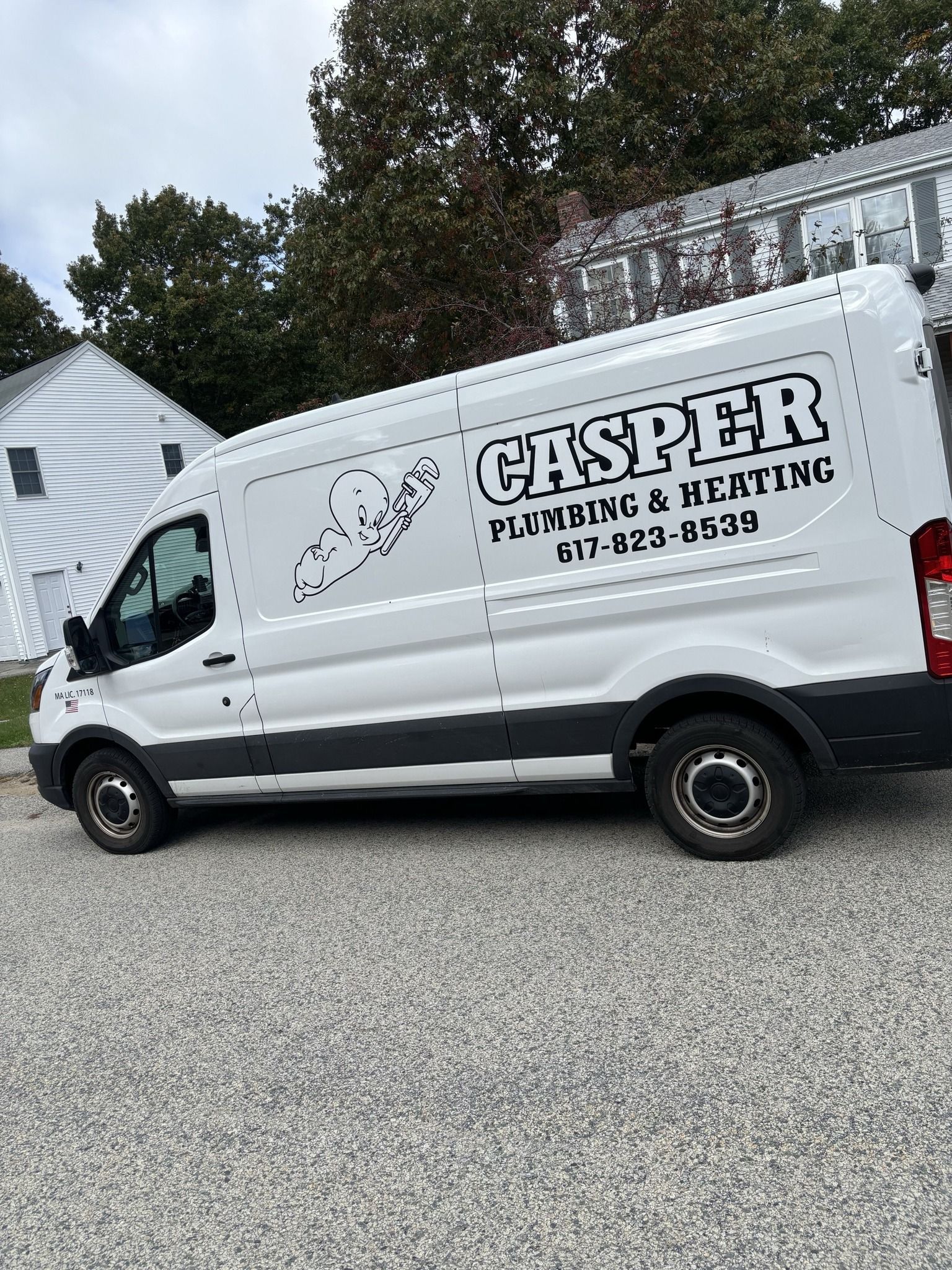 A white Casper Plumbing & Heating work van parked on a gravel surface next to a white house.