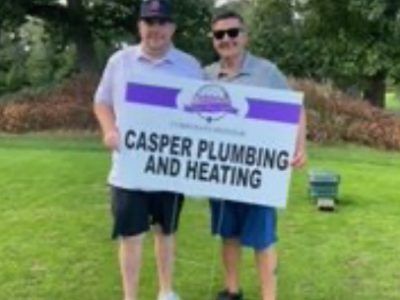 Two people standing on a grassy field holding a sign that reads 