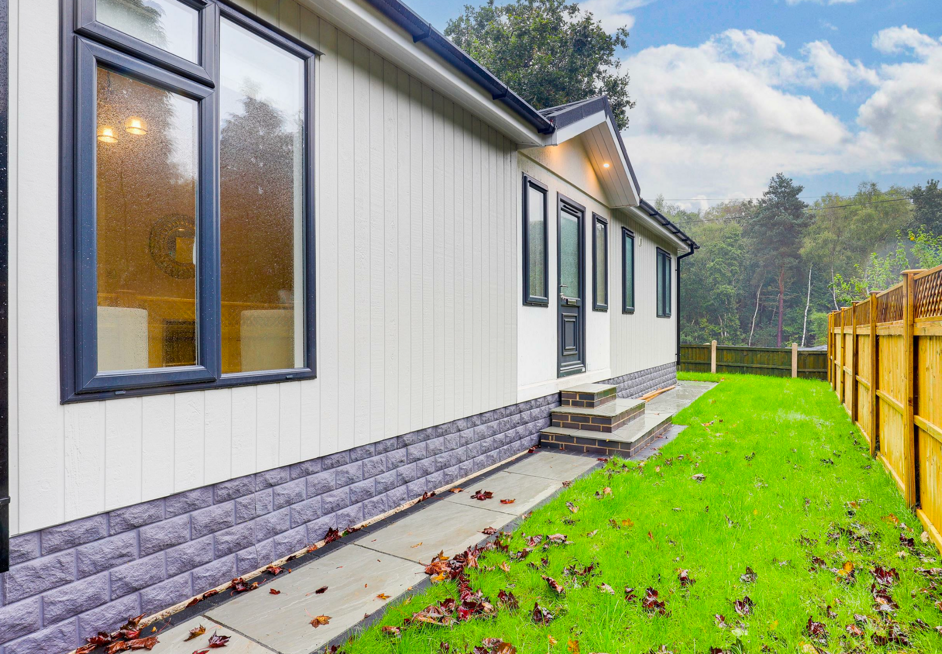 A white house with a wooden fence and a tree in front of it.