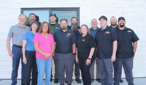Group of people standing outside a building, posing for a team photo.