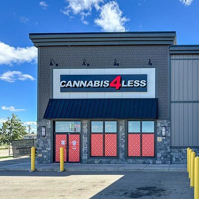 Cannabis 4 Less store exterior with blue sky. Gray and black building with red windows.