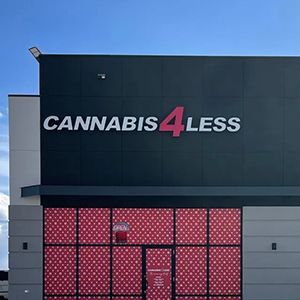 Cannabis 4 Less store exterior with sign and red patterned window. Gray and black building.