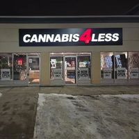 Cannabis 4 Less storefront at night, lit sign, glass doors, snow on ground, 