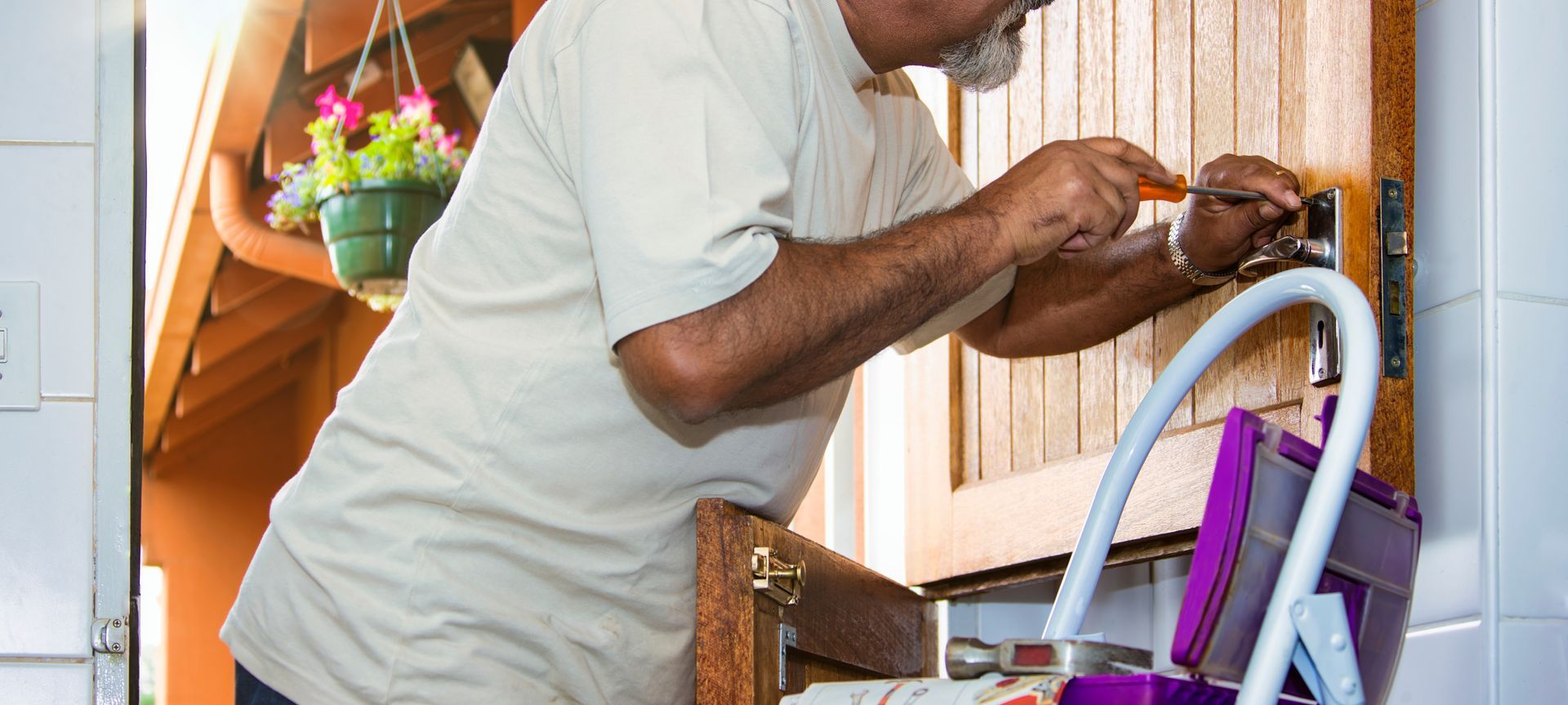 Locksmith fixing a wooden door lock with a hammer.