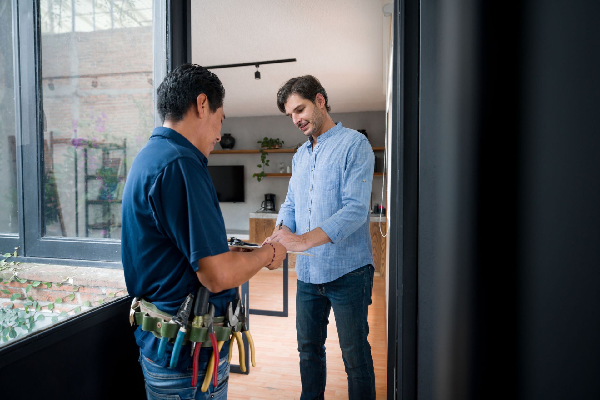 Homeowner shaking hands with handyman wearing tool belt at house entrance. Homeowner shaking hands with handyman wearing tool belt at house entrance.