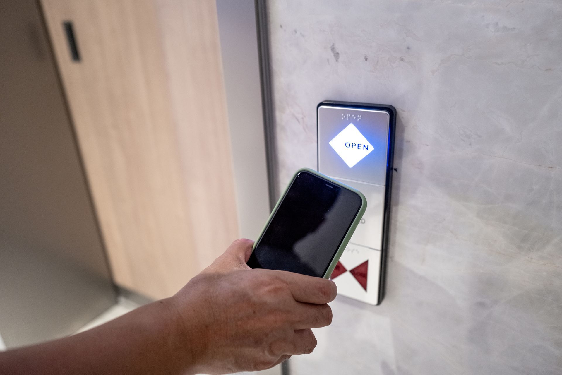 Hand holding a mobile phone to open the automatic induction lock of the door. Hand holding a mobile phone to open the automatic induction lock of the door.