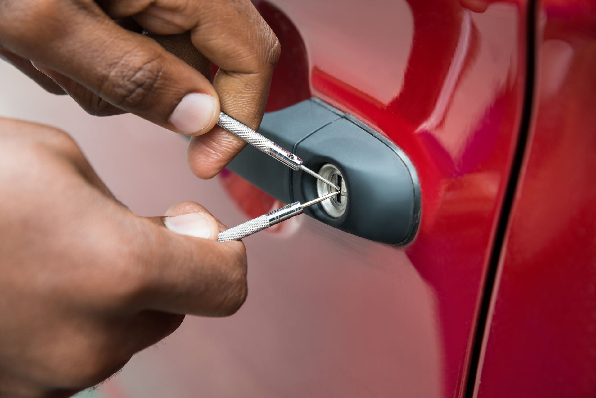 Close-up of person hand opening car door with lockpicker.