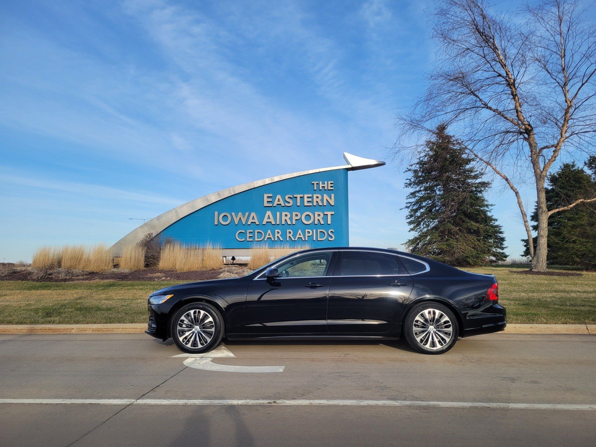A black Volvo S90 parked in front of a sign in Iowa City