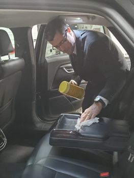 A man in a suit is cleaning the inside of an Iowa City sedan with Xquisite Limo