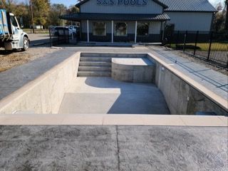 A swimming pool is being built in front of a building that says sas pools