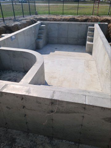 A large concrete pool is being built in a backyard.