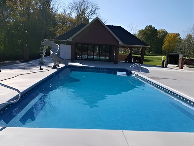 A large swimming pool with a house in the background