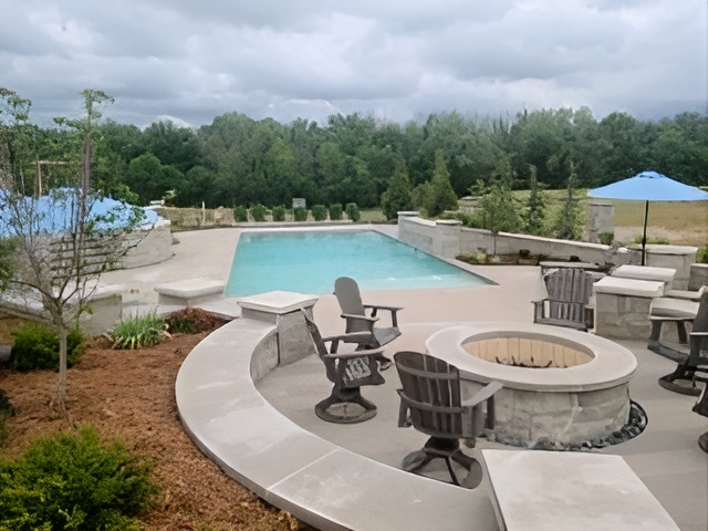 A swimming pool with a fire pit and chairs around it