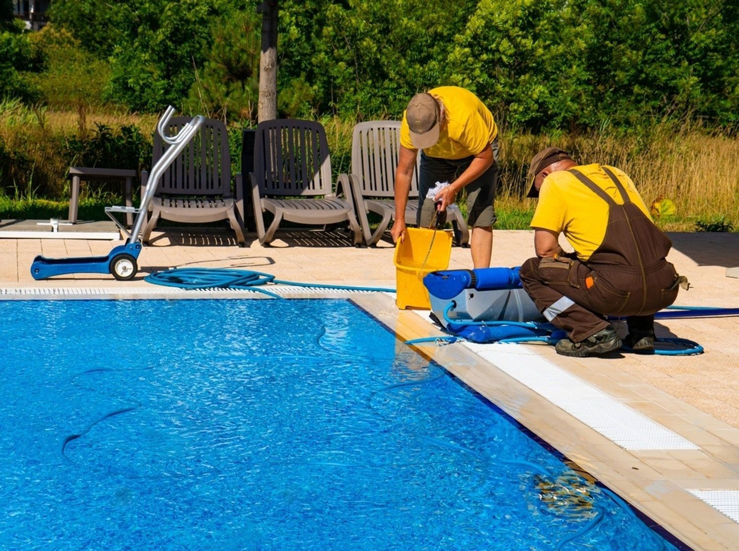 Two men are cleaning a swimming pool with buckets.