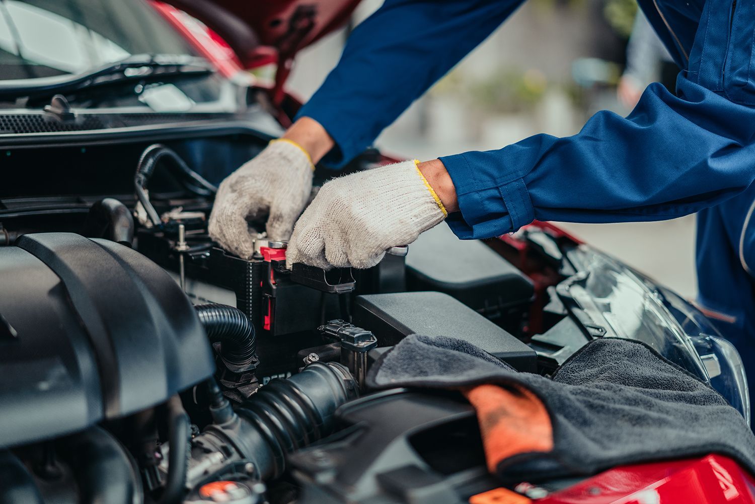 Mechanic inspecting and tightening battery terminal in workshop.