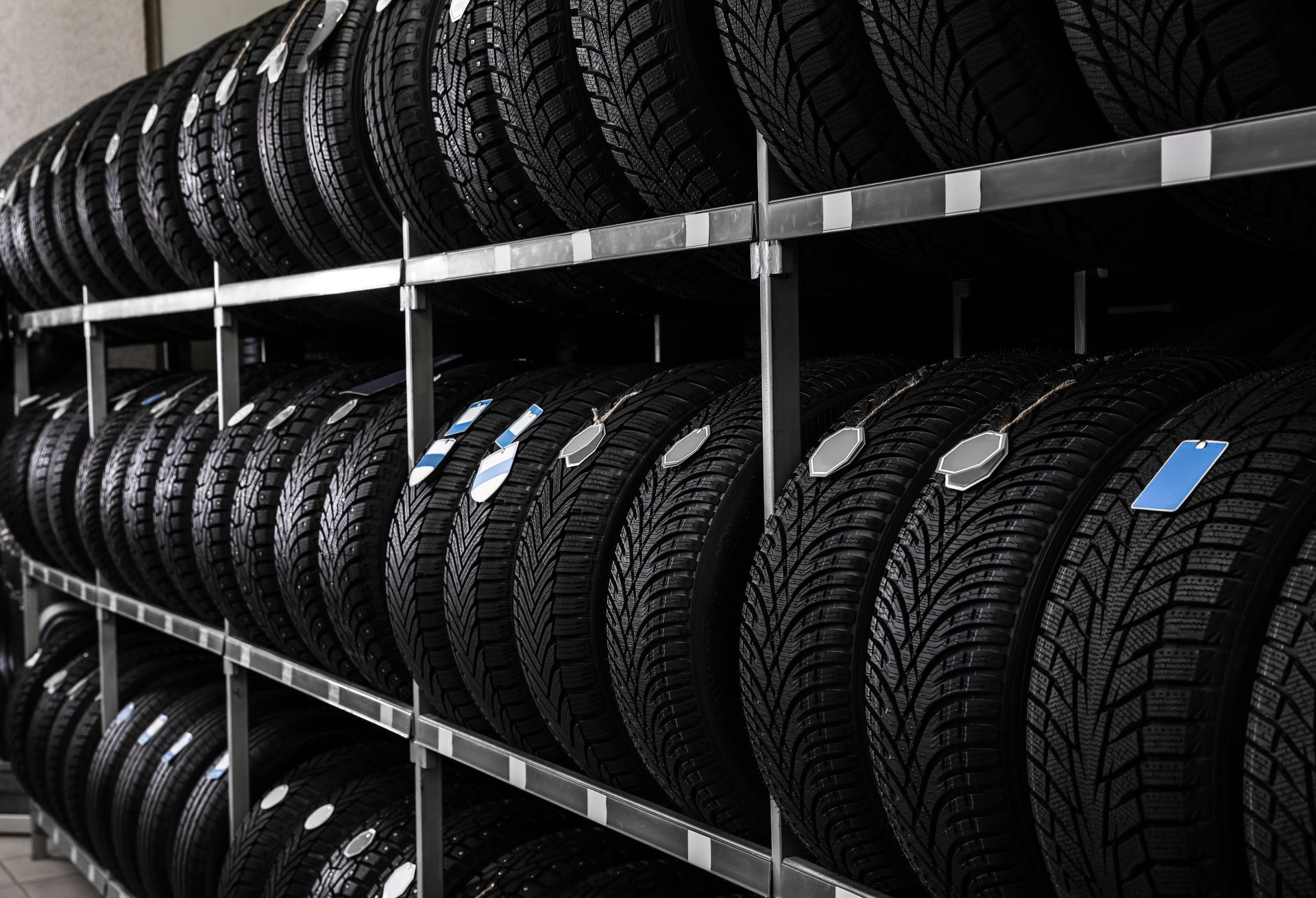 Rows of tires are placed on metallic racks inside an auto store.