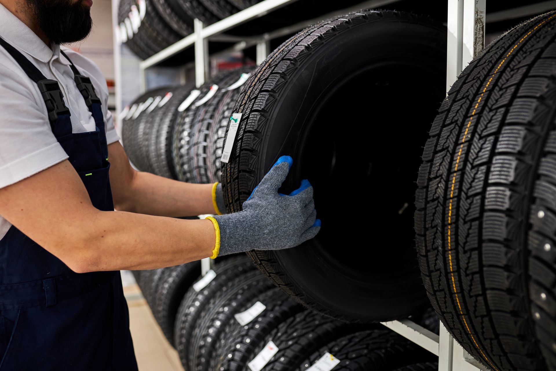 Mechanic selecting car tire in auto repair shop.