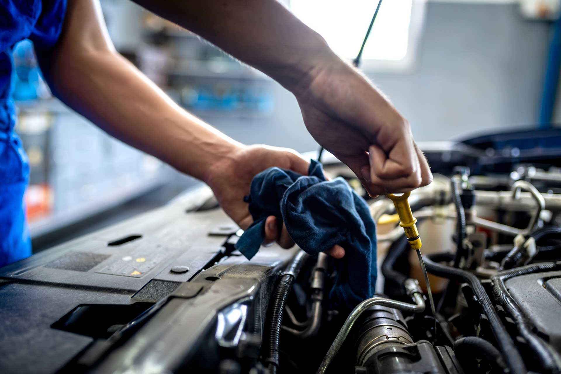 The mechanic inspects the oil level and works on the engine at the service station.