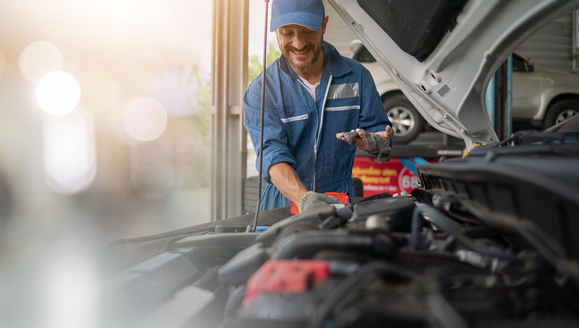 A mechanic works on a car engine in an auto repair shop