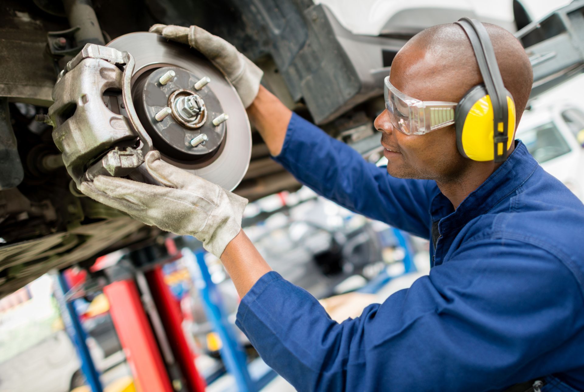 Certified mechanic performing brake repair on a car’s braking system.