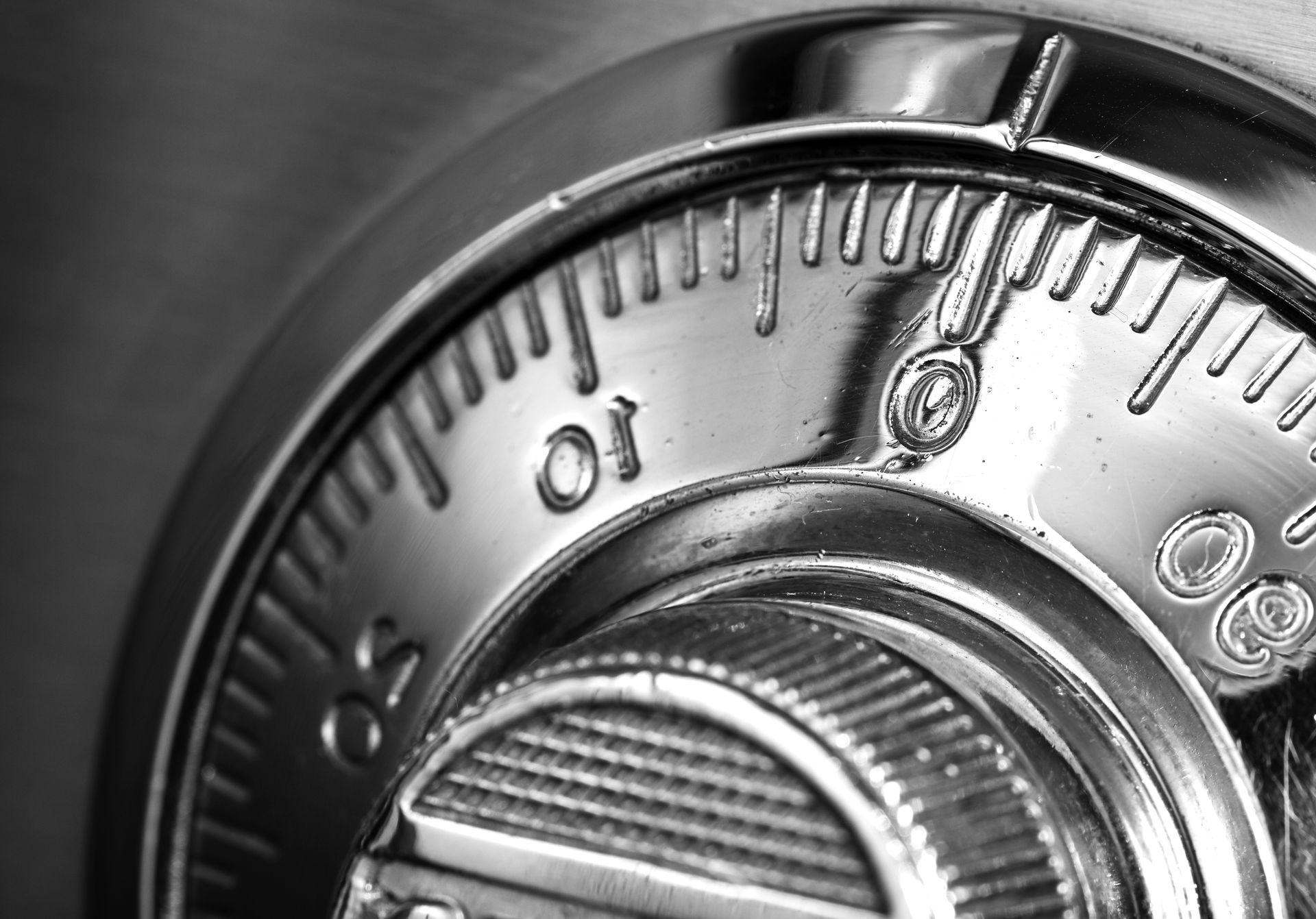 A close-up, black-and-white view of a metallic safe dial showing numbers around its circular edge.