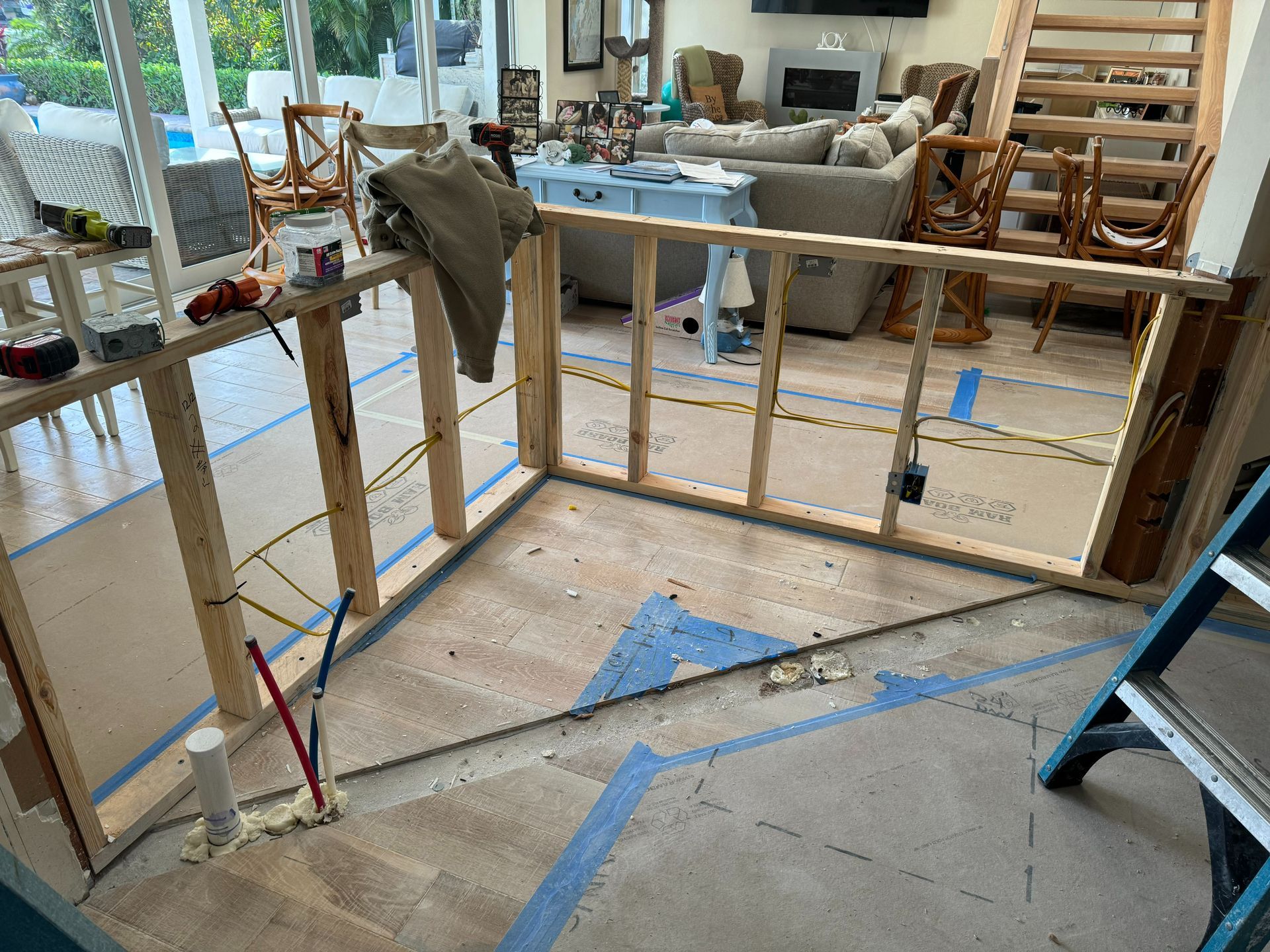 Interior renovation with new wooden framing, exposed wires, and blue tape on floor.