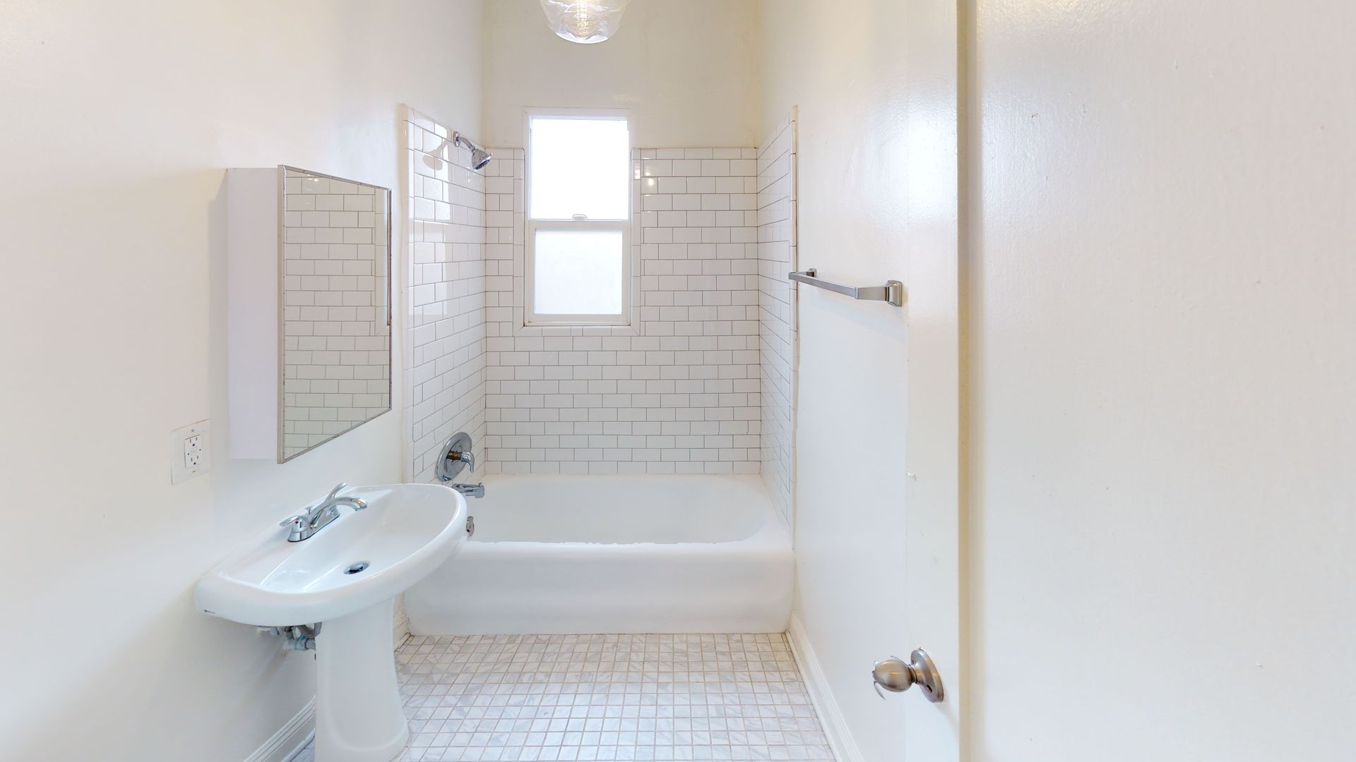 White bathroom with a tub, sink, and window.