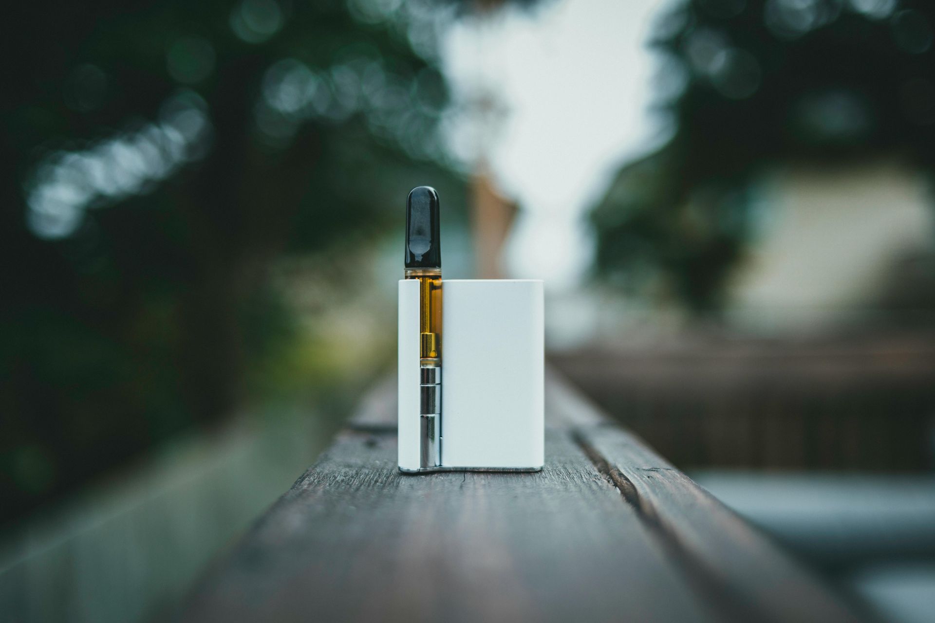 A vape pen is sitting on a wooden table.