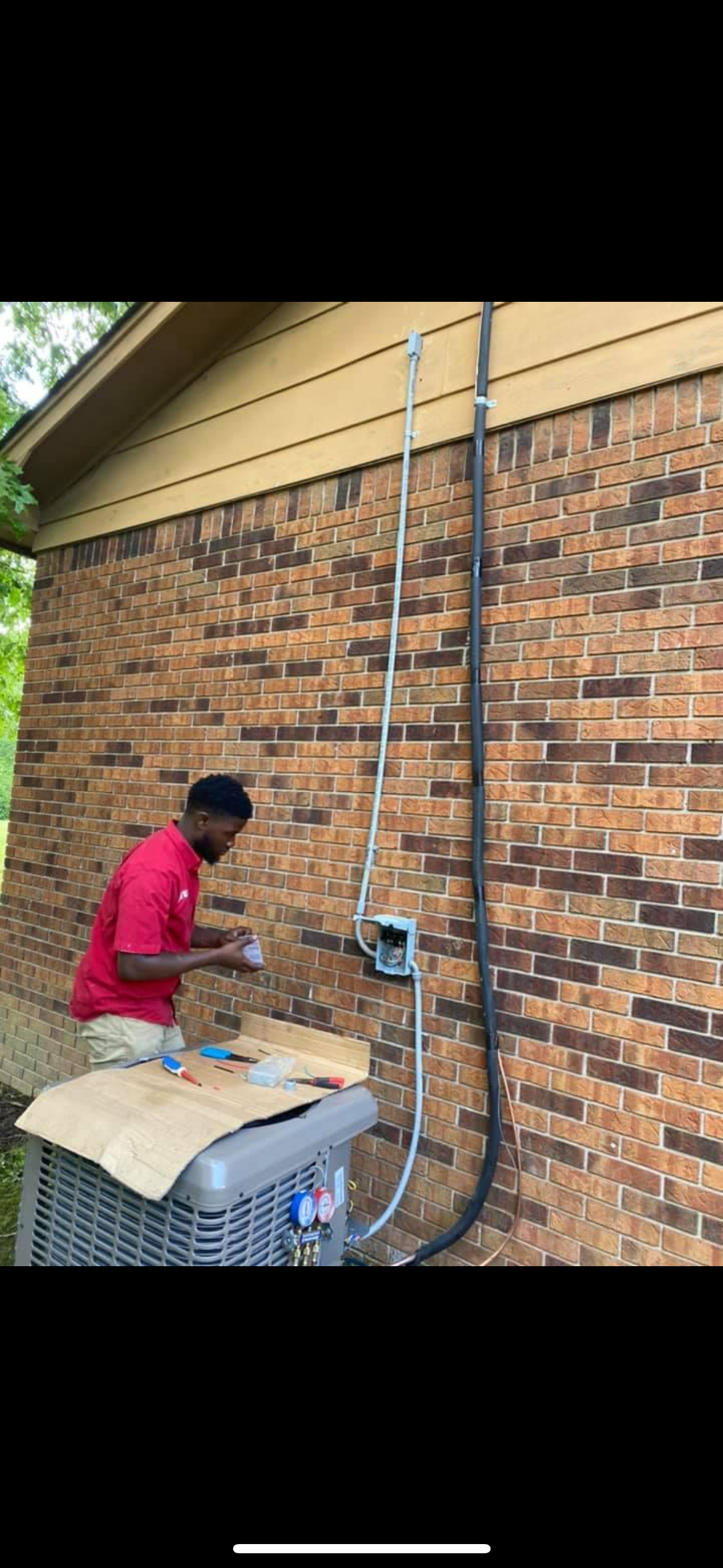 A man is working on a brick wall next to an air conditioner.
