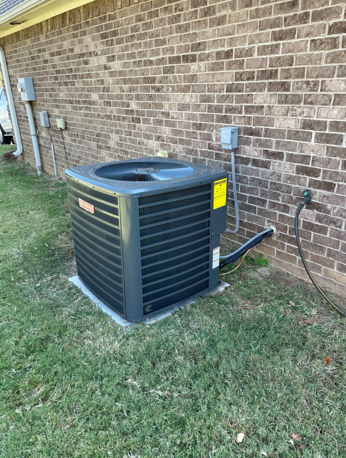An air conditioner is sitting on the side of a brick building.