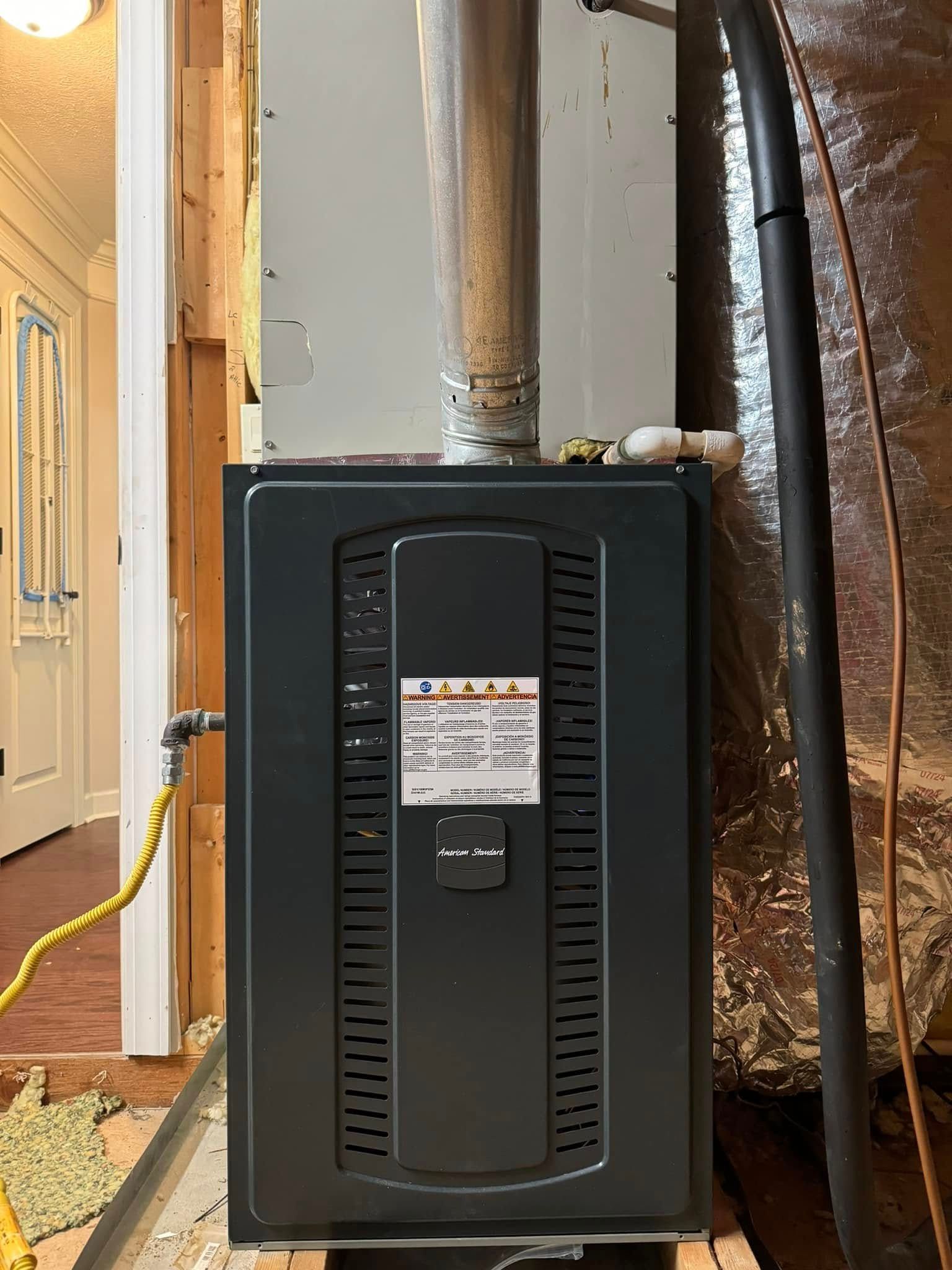 A black furnace is sitting in a room next to a door.