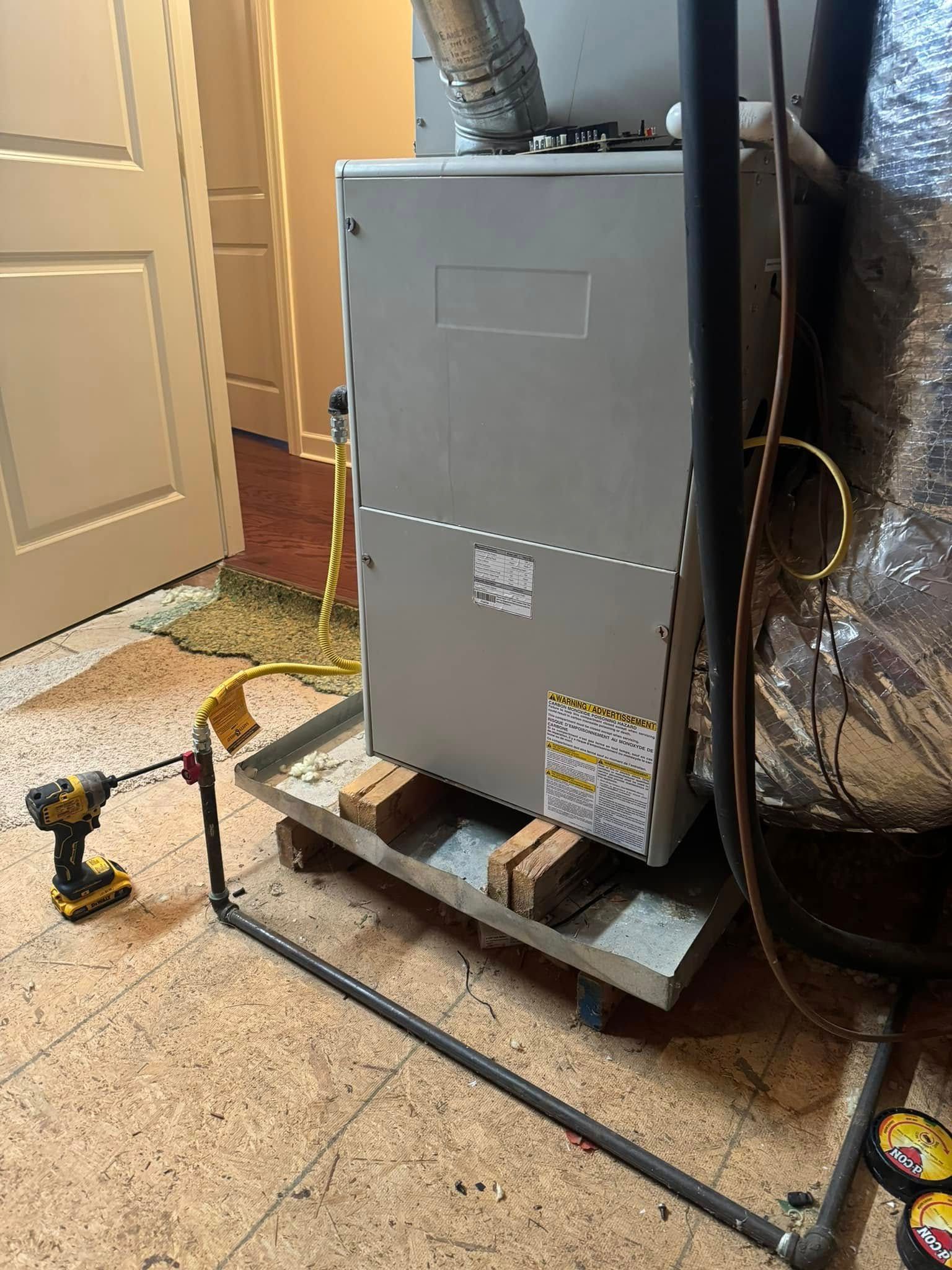 A drill is sitting next to a furnace in a basement.