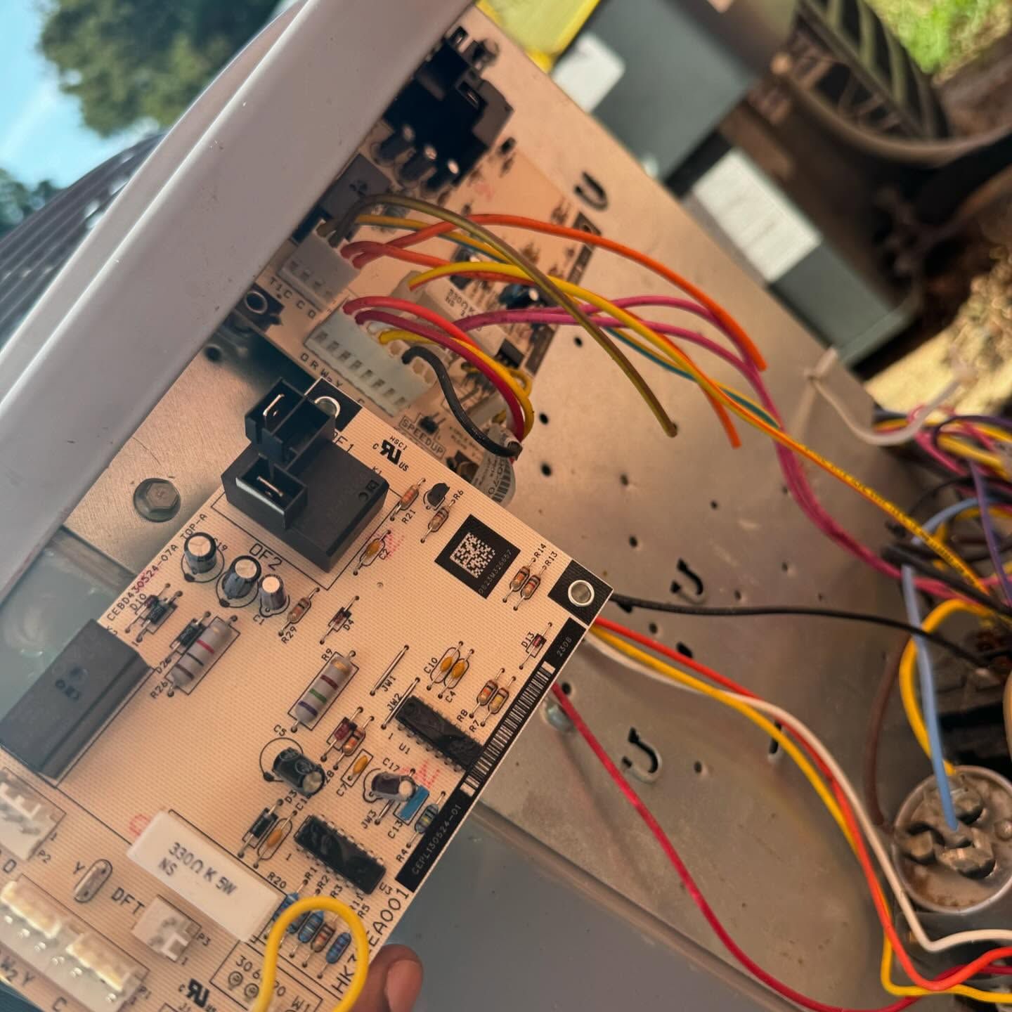 A person is holding a motherboard with a lot of wires attached to it