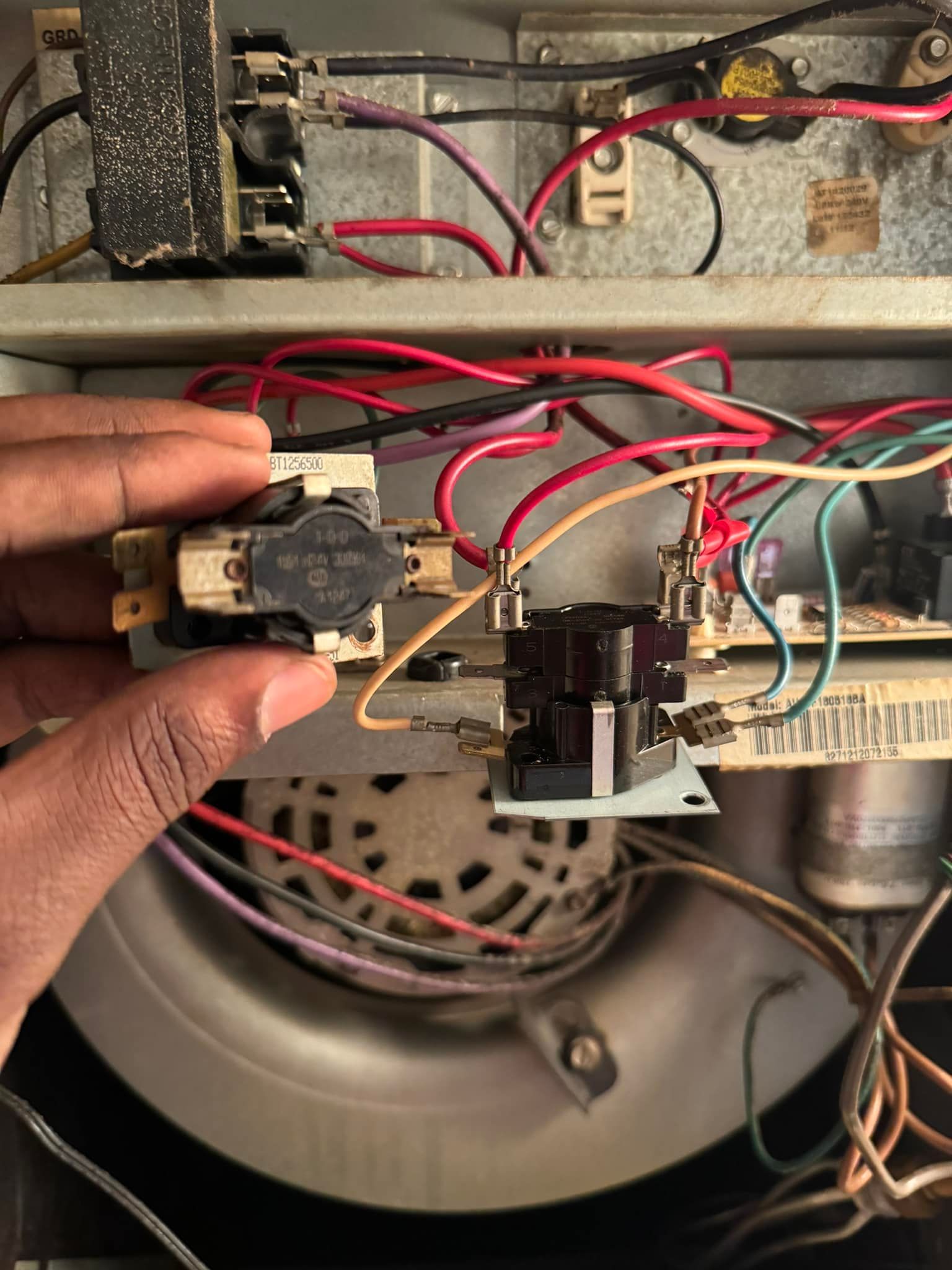 A person is holding a switch in their hand in front of a bunch of wires.