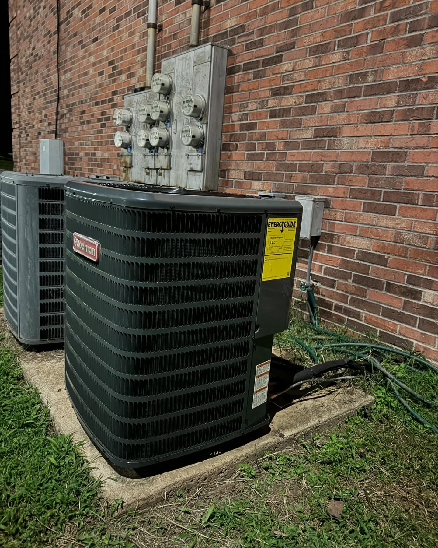 Two air conditioners are sitting on the side of a brick building.